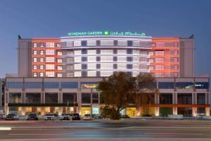 a large building with a sign on top of it at Wyndham Garden Muscat Al Khuwair in Muscat