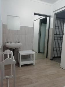 a bathroom with a sink and a mirror and a stool at Oakwood Lodge in Bloemfontein