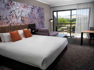 a bedroom with a large bed and a living room at Novotel Barossa Valley Resort in Rowland Flat