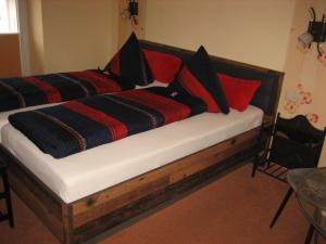 una cama de madera con almohadas rojas y negras. en Schusters Lindenhof en Bautzen