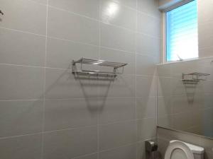 a white tiled bathroom with a toilet and a window at MD Boutique Hotel in Kampar +46 photos