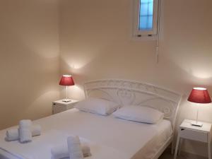 a bedroom with a white bed with two lamps at Monolithos Villas in Kipri