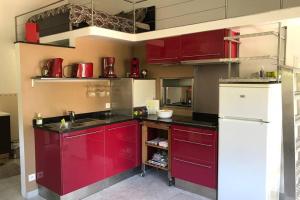 een keuken met rode kasten en een witte koelkast bij L'Annexe in Menton