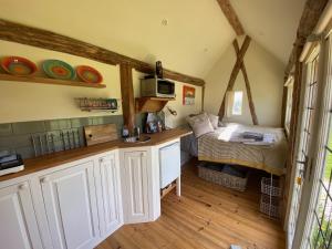 a small room with a bed and a kitchen at The Hat's Hut in Mixbury