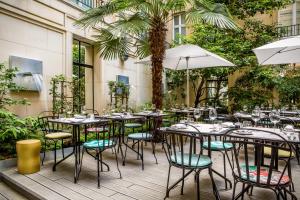 an outdoor patio with tables and chairs and palm trees at Sofitel Paris Le Faubourg in Paris