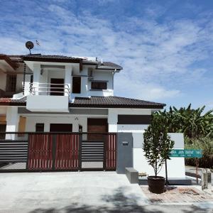 a white house with a gate in front of it at Just Austin Guesthouse in Ipoh