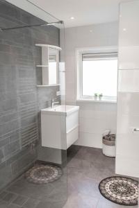 a white bathroom with a sink and a window at Bungalow Sunny, lekker uitwaaien op het strand! in Callantsoog +13 photos