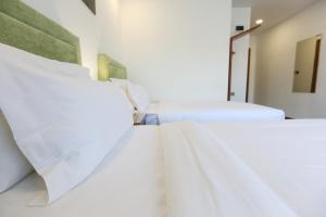 two beds in a room with white sheets at Sunrise Hotel in Tashkent
