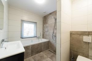 a bathroom with a tub and a sink and a shower at Onder de Pannen in Hollum +7 photos