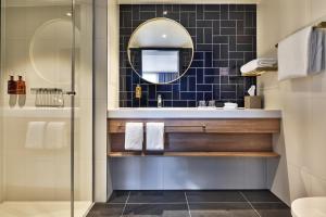 bagno con lavandino e specchio di Staybridge Suites The Hague - Parliament, an IHG Hotel a L'Aia