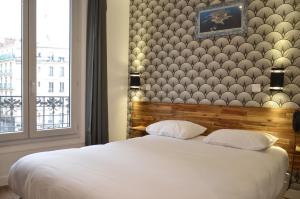 a bedroom with a large white bed with a wall at Hôtel De La Perdrix Rouge in Paris