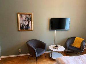 een kamer met 2 stoelen en een tv aan de muur bij First Hotel Statt in Karlskrona