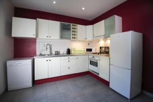 a kitchen with white appliances and red walls at Maison tendance avec jardin, centre village, Alpilles, familles in Eyragues