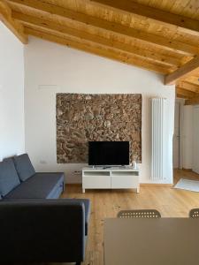 sala de estar con pared de piedra y TV en OSTERIA al CANTONACCIO APARTMENTS, en Brusimpiano