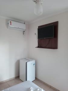 a room with a refrigerator and a flat screen tv at Pousada 4 Estações in Caldas Novas
