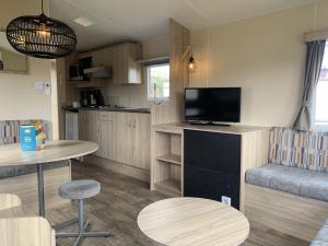 ein Wohnzimmer mit einem TV, einem Tisch und Stühlen in der Unterkunft Beach Resort Kamperland - 167 in Kamperland