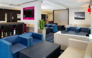 una sala d'attesa con sedie blu e un tavolo di Holiday Inn Express London - Wandsworth, an IHG Hotel a Londra