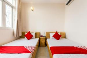 two beds in a room with red pillows at Ph&uacute; Ho&agrave;ng Nam Hotel in Ho Chi Minh City