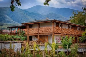 a large wooden house with mountains in the background at Къщи за гости Сноуфлейк Snowflake Chalet and Snowflake Lodge in Bansko