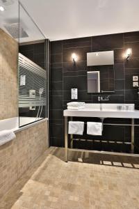 La salle de bains est pourvue d'un lavabo, d'une baignoire et d'un miroir. dans l'établissement KYRIAD Périgueux - Boulazac, à Saint-Laurent-sur-Manoire