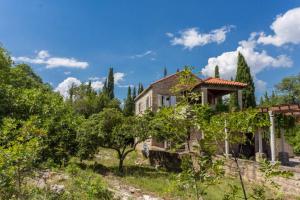 een oud huis in een veld met bomen bij Sleep & Fly Cottage in Čilipi