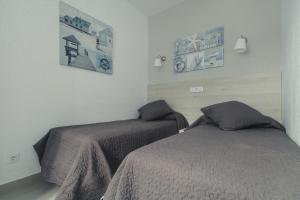 a bedroom with two beds and pictures on the wall at Puerto Mogan Apartment in Puerto de Mogán