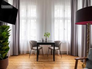 einen Tisch und Stühle in einem Zimmer mit Fenstern in der Unterkunft Apartments Berlin Bornimer Straße in Berlin