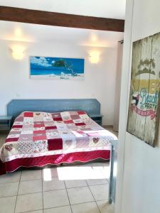 a bedroom with a bed with a red and white quilt at Le Maset in Saintes-Maries-de-la-Mer