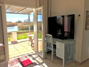 een woonkamer met een televisie en een glazen schuifdeur bij Le Maset in Saintes-Maries-de-la-Mer