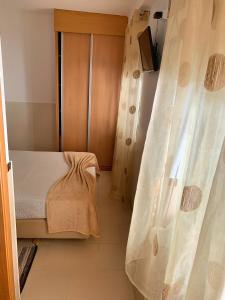 a small bedroom with a bed and a curtain at Duarte Houses - Casa T1 - com vista mar in Nazaré