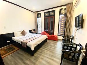 1 dormitorio con 1 cama, TV y silla en Khách sạn Hoàng Gia, en Thái Bình