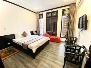 a bedroom with a bed and a tv and a chair at Khách sạn Hoàng Gia in Thái Bình