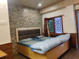 a bedroom with a bed and a brick wall at Mehdudia Guest House in Shimla