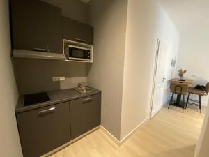 a small kitchen with a sink and a microwave at Aparthotel Charlotten in Hannover