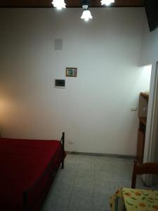a bedroom with a red bed and a white wall at Casa del vico in Catania