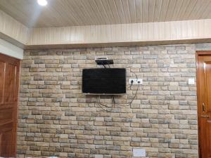 a brick wall with a tv on a wall at Mehdudia Guest House in Shimla