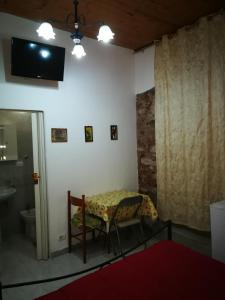a room with a table and a television and a bathroom at Casa del vico in Catania