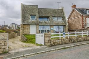 een stenen huis met een wit hek ervoor bij Ker Paul et Ker Julien- appartements vue mer in Erquy