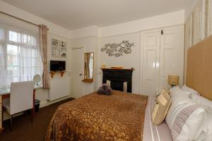1 dormitorio con cama, escritorio y chimenea en Robertsbrook Guest House en Swanage