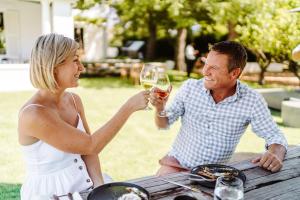 Ein Mann und eine Frau sitzen am Tisch und trinken Wein. in der Unterkunft Last Word Franschhoek in Franschhoek