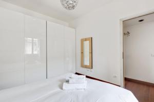 a white bedroom with a bed with a mirror at Easylife - Strategic apt in Washington in Milan