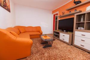 a living room with an orange couch and a tv at BORNA in Crikvenica