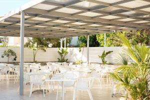 a group of tables and chairs under a white umbrella at Lantiana Gardens ApartHotel in Protaras