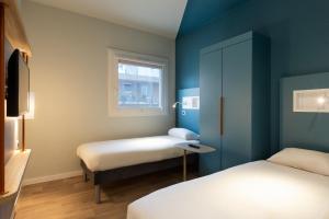 a small room with two beds and a window at Ibis Budget Bourgoin Jallieu Centre in Bourgoin