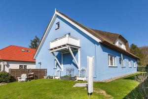 a blue house with a white balcony on a yard at Mohnblume in Zirkow