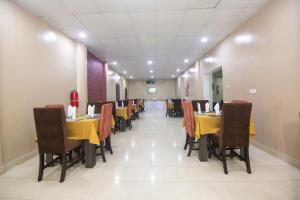a dining room with yellow tables and brown chairs at Belmont Hotel in Wupa