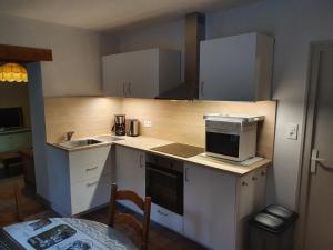 a small kitchen with white cabinets and a microwave at Le Coeur Du Moulin in Saint-Aubin-le-Monial