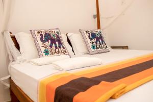a bedroom with a bed with pillows on it at TEMBO Cottage Wilpattu in Wilpattu