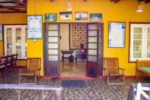 a room with a yellow wall with a door and chairs at TEMBO Cottage Wilpattu in Wilpattu