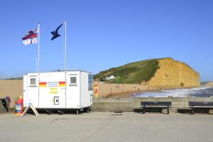 a trailer parked next to a beach with a flag at Westpoint Apartments in West Bay